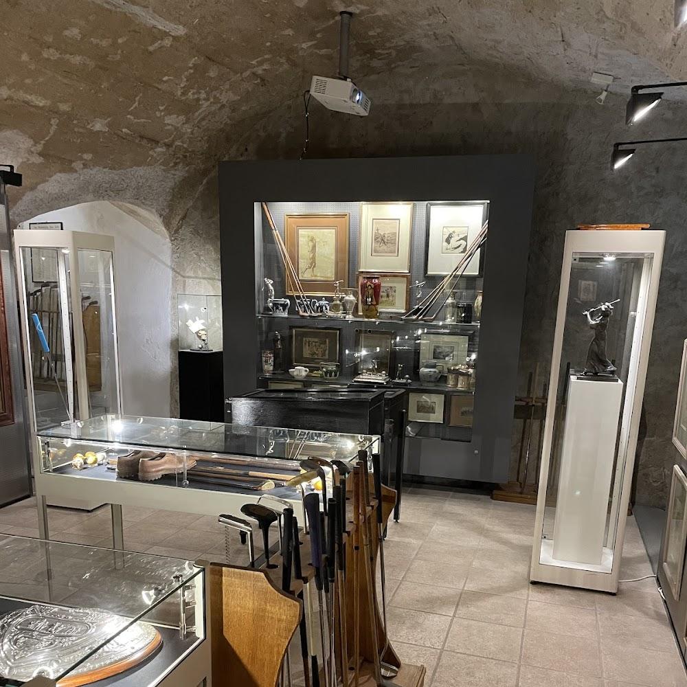 A room with golf clubs, a display case with a sculpture, and a display cabinet with golf memorabilia.
